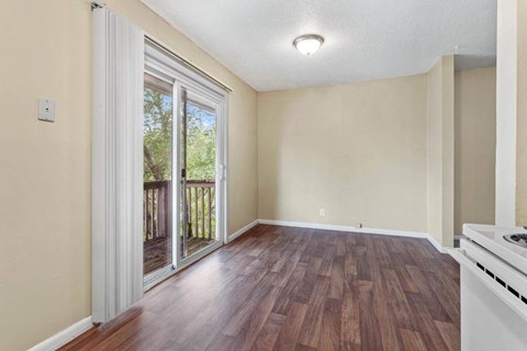 A room with a wooden floor and a sliding glass door leading to a balcony.